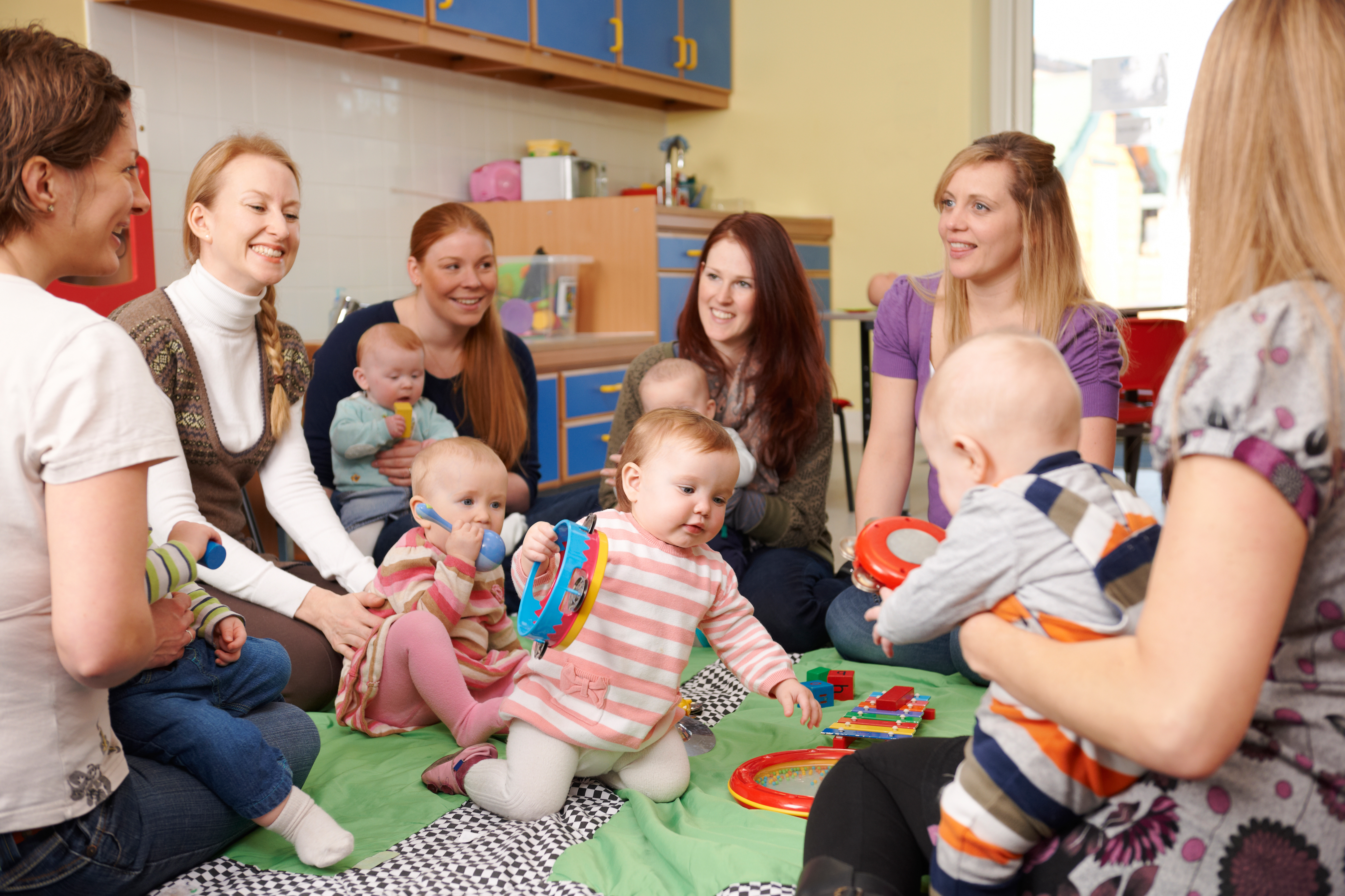 Group of women sitting in a circle with babies playing