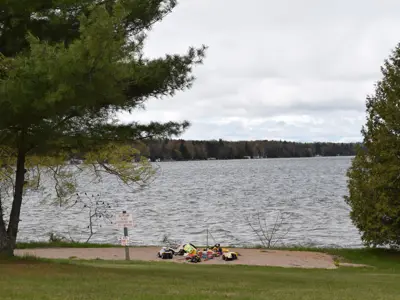 A park beach with toys in the sand and trees surrounding it