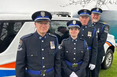 Members of the Honour Guard stand in front of an emergency vehicle.