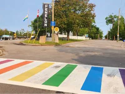 Street view with a crosswalk with rainbow stripes in the foreground.