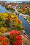 Aerial photo of waterway surrounded by trees with vibrant orange and green fall foliage.