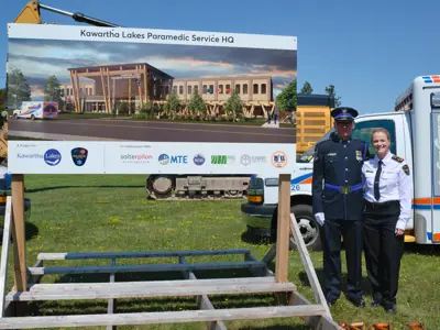 Chief and honour guard posing beside new paramedic HQ sign