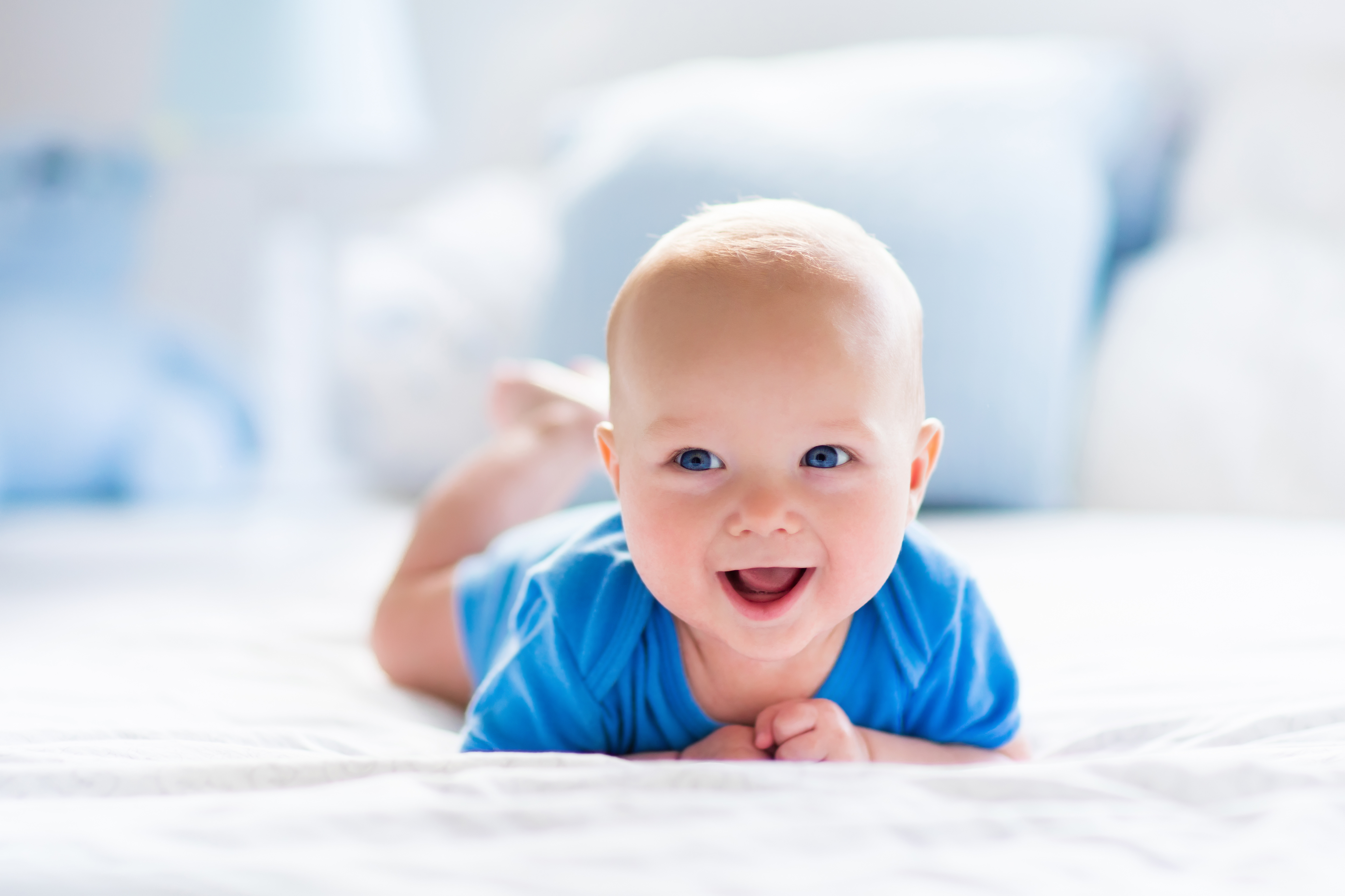 Baby crawling on white blanket or carpet.