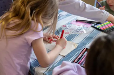 Children sitting and drawing at table with markers