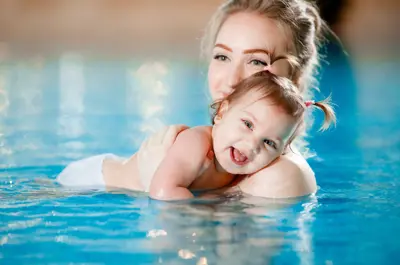 Women holding young child in a pool